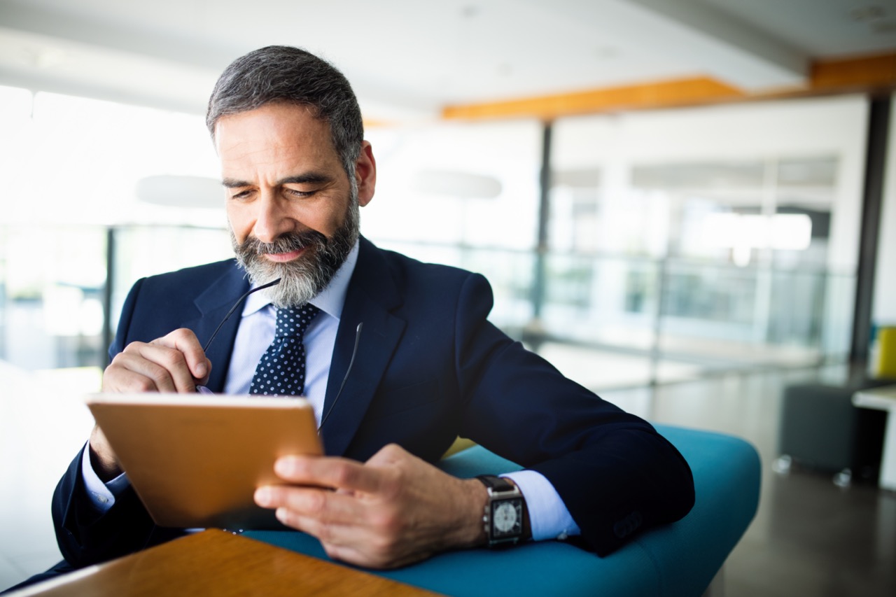 Elegant business multitasking multimedia man using devices at office